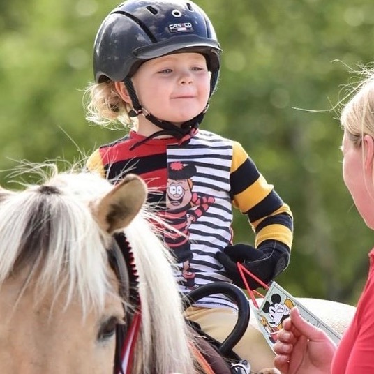 Kleinkind mit Reithelm auf einem Fjordpony